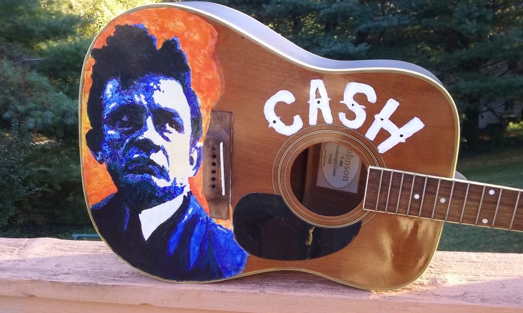 This acoustic guitar has been painted with an image of a young Johnny Cash.